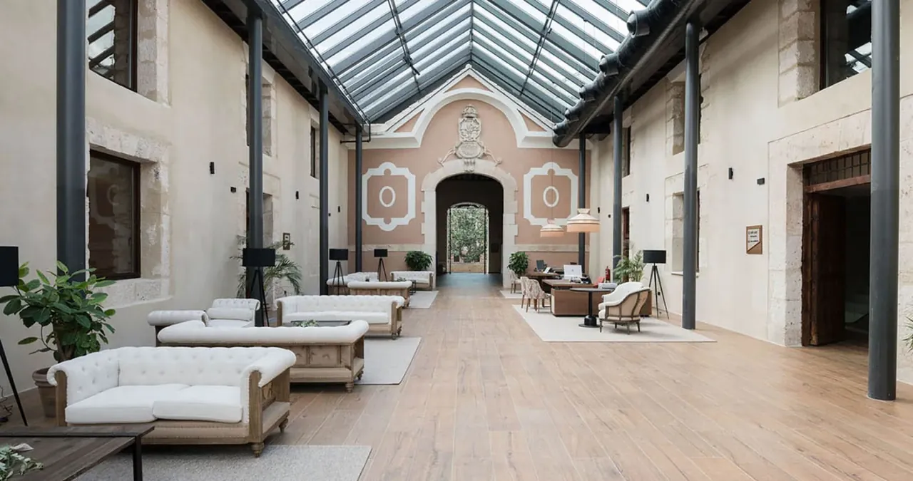 La galería luminosa del hotel, con sofás blancos bajo un techo de cristal