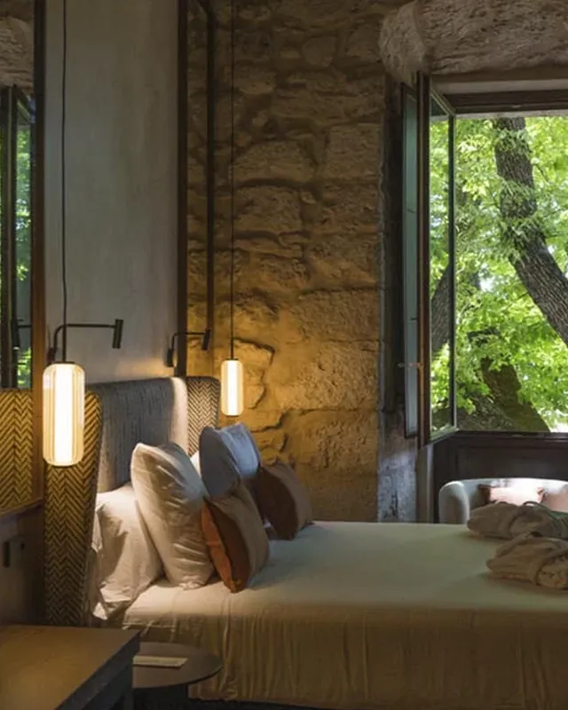 Una habitación con muros de piedra y una ventana abierta a los árboles
