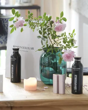 Rosas, una vela y botellas de agua sobre una mesa de madera
