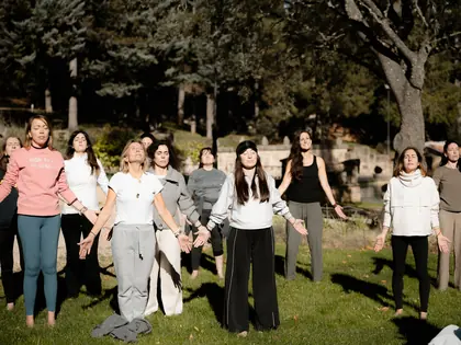 Las asistentes, en círculo al aire libre, con los brazos abiertos